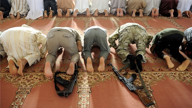 Libyjci i se zbran�mi kle�í p�i modlitb� v me�it� v pou�tním m�st� Bin D�awad.