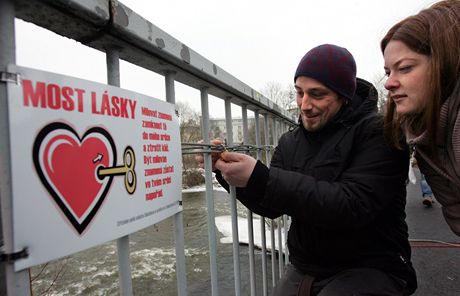 Martin a Pavlína zamykají svj visací zámek na most lásky v Sokolov. Klí