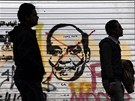 Egypané procházejí kolem graffiti s pekrtnutým obliejem marála Husajna...
