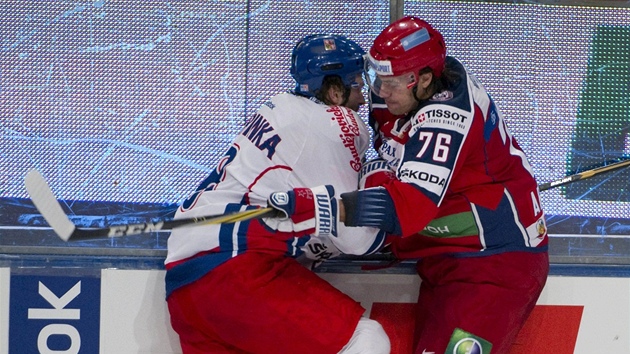 KAM SE TLA͊? esk hokejista Michal Barinka v souboji u mantinelu s Rusem Jevgenijem Aruchinem.