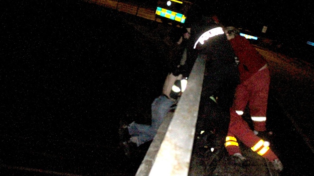 Policisté, posádka sanitky a hasii drí mladíka bezmocn visícího z mostu ve
