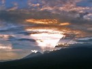 Paprsky zapadajícího slunce zezadu osvcují sopku Gunung Rinjani v Indonésii