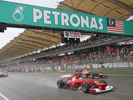 KUPEDU. Fernando Alonso s erveným Ferrari uhání pod temným malajským nebem za...