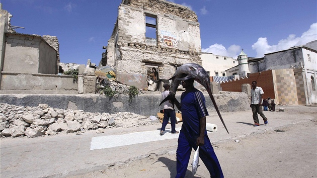 Somálský rybář kráčí se svým úlovkem válkou poničeným Mogadišem (27. března