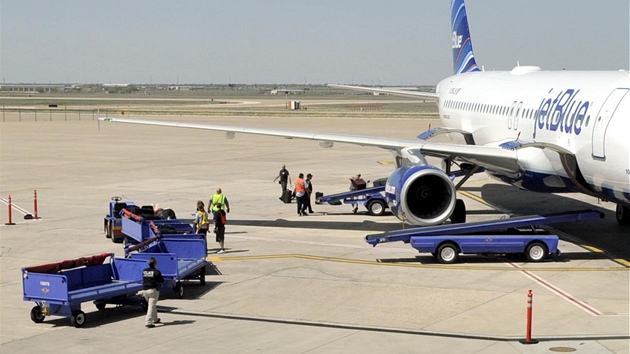 Zamstnanci letit v Amarillu vyndvaj zavazadla z letadla spolenosti JetBlue, kter muselo neekan pistt v Texasu pot, co se zhroutil kapitn stroje (27. bezna 2012)