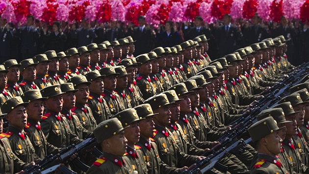Vojáci pochodují ped angaovanými severokorejci, kteí jim mávají kvty.