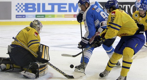 ZÁVAR. Mikko Koivu z Finska se tlaí ped védského brankáe Jhonase Enrotha a