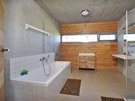 Koupeln v pízemí také vládne pohledový beton, fasádu tvoí borovicové