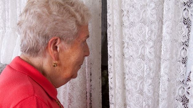 Seniorka vyhlíející z okna
