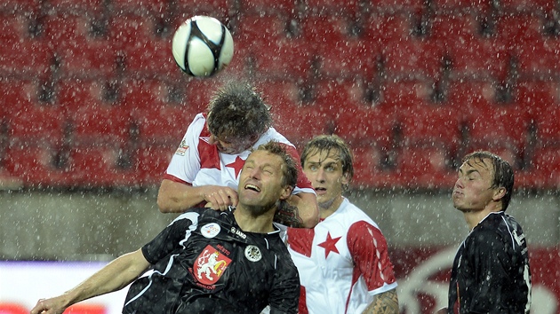 HLAVIKA V DETI. Slvista Zbynk Pospch (v ervenoblm) a krlovhradeck Milan Fukal bojuj o m, zatmco na stadion v Edenu padal hust d隝.