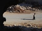 Syrský chlapec kráí kolem rozbombardovaných dom ve mst Taftanaz, nedaleko
