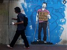 Mu kráí kolem grafitti v centru Atén, na kterém je postava s berlemi a