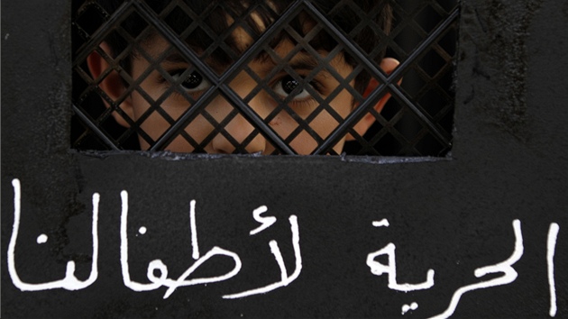 Chlapec dr ped obliejem transparent znzorujc dvee vzen, na nich je arabsky napsno "Svobodu pro nae dti". 