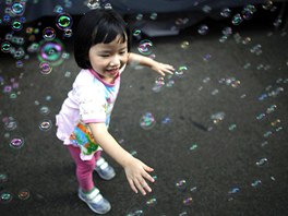 Dvátko si v centru Hongkongu neruen hraje s bublinkami, zatímco okolo nj...