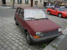 Auto s rozbitým sklem stojí v ulici Dejvická blízko kiovatky Jaselská na