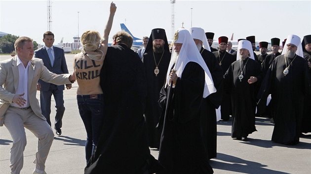 Na patriarchu rusk pravoslavn crkve Kirilla se na letiti v Kyjeve vrhla aktivistka z feministick organizace Femen s odhalenmi adry. Kirill stoj uprosted v bl pokrvce hlavy (26. ervence 2012)