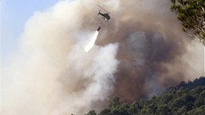 Helikoptéra práv svrhla balík vody na hoící les u msta Tarrades ve panlsku