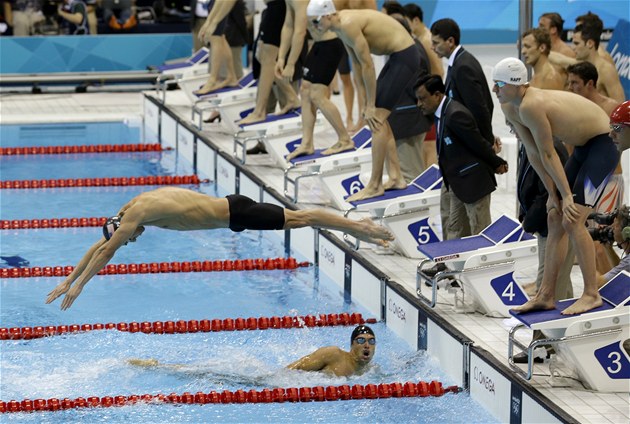 Michael Phelps skáe do bazénu pi závodu tafet.