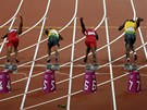 Láhev leící na dráze za bloky v okamiku startu olympijského finále stovky.