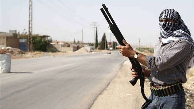 Po zuby ozbrojený syrský Kurd pózuje ped nov vytvoeným checkpointem ve mst