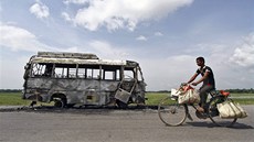 Ind jede na kole kolem autobusu spáleného bhem nepokoj ve mst Rongia v