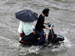 VODNÍ SKÚTR. Ind se snaí projet zatopenou ulicí bhem monsunu ve mst Dammú...