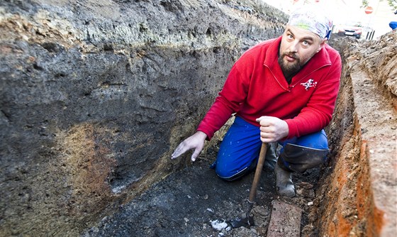 Archeolog Michal Soukup ukazuje na oranov propálenou vrstvu hlíny, kde byla