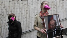 Opoziní aktivistky pózují s Putinovým portrétem ovázaným smutení ernou malí.