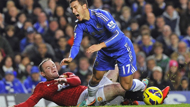 FAUL ZA LUTOU. Wayne Rooney, stelec Manchesteru United, nedovolen zastavuje Edena Hazarda z Chelsea.