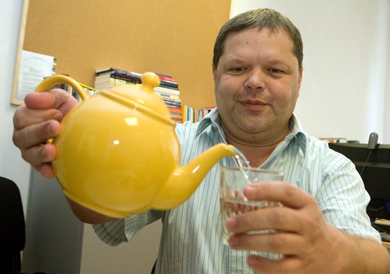 Petr Walla hostí klienty ve své poradně čistou vodou. Ve žluté keramické
