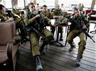 Izraeltí vojáci v kibbutzké kavárn sledují televizní zpravodajský poad
