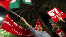 Izraelec mává palestinskou vlajkou bhem shromádní v Tel Avivu na podporu