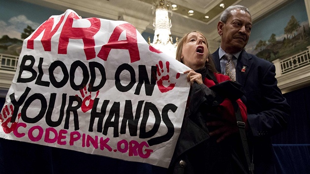 Ochranka vyvd enu, kter protestuje proti vystoupen vkonnho editele NRA Waynea La Pierra ve Washingtonu (21. prosince 2012)