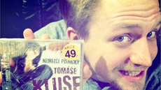 Tomá� Klus se fale�nému cédé�ku se svými písni�kami sm�je. 