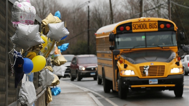 Typický americký školní autobus projíždí městem Newtown kolem provizorního památníku obětí střelby ve škole Sandy Hook. (18. prosince 2012) 
