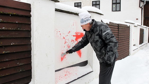 Majitel sousedn nemovitosti Stanislav ern odstrauje symboly, kter neznm sprejer nastkal o vkendu na plot pobl Zemanovi chalupy.