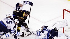 Ond�ej Pavelec z Winnipegu vytla�uje puk, který se za jeho záda sna�í dostat