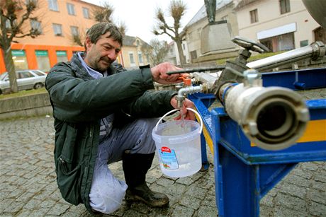 Milan Catargiu si nabírá vodu u cisterny na námstí v Miroticích na Písecku. Pitnou vodu sem musí ji zhruba týden dováet. Vodu ve vrtech, odkud je zásobováno msto, kontaminovala rozvodnná íka Lomnice. | foto: Slavomír Kube, MAFRA