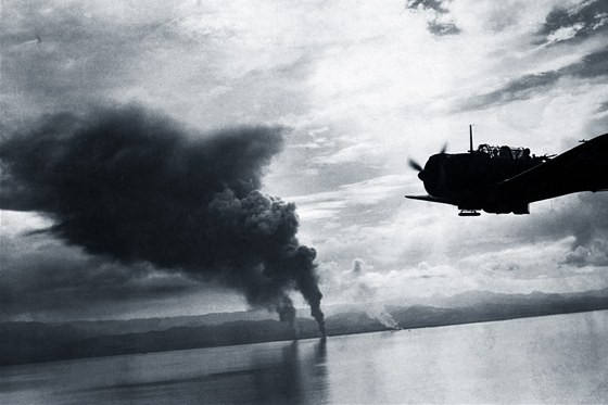 Bombardér Douglas SBD Dauntless amerického námořnictva letí nedaleko hořících