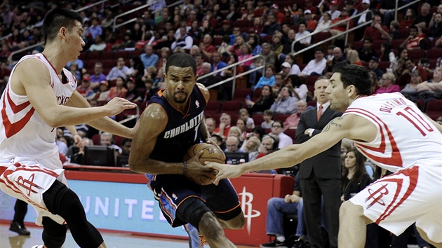 Ramon Sessions z Charlotte pronika obranou Houstonu, pronsleduj ho Jeremy Lin (vlevo) a Carlos Delfino.