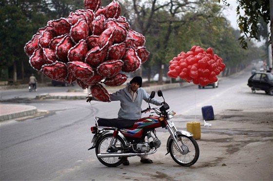 Mladík tlaí motocykl s valentýnskými balónky v pakistánském Islámábádu. (14.