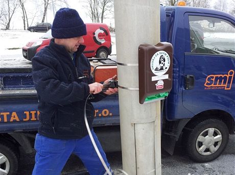 Pracovník Slueb msta Jihlavy upevuje zásobník na pytlíky v ulici S. K.