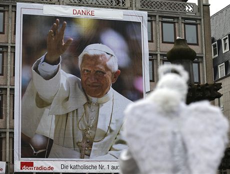 Umlec pevleený za andla pózuje ped obím portrétem papee Benedikta XVI. v
