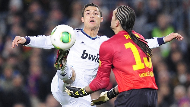 KDO S KOHO. Cristiano Ronaldo z Realu Madrid se pokou doshnout na m, kter se sna lapit i brank Barcelony Jos Manuel Pinto. 