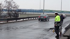 Policisté hlídkují u po�kozené komunikace.