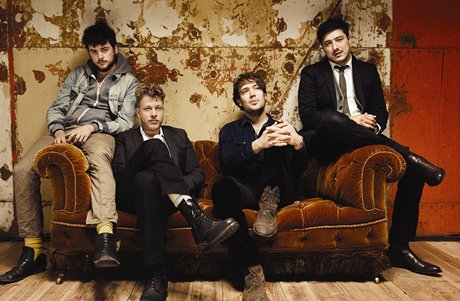 Mumford & Sons. Zpovídaní Ted Dwane a Ben Lovett sedí na gaui. 