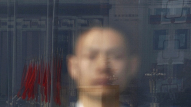nsk policista sleduje hemen v centru Pekingu ped  Palcem lidu, kde zased nsk parlament (5. bezna 2013)
