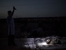 Syan osvtluje baterkou tlo mue zabitého bhem boj v Aleppu (íjen 2012)