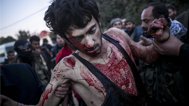 Obyvatel Aleppa pomhaj jednomu z bojovnk zrannmu v bojch s Asadovmi jednotkami (prosinec 2012)