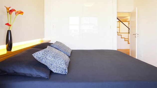 Byt 1: Úložné skříně v ložnici jsou bílé, nenápadné, pozornost se barevností zaměřuje na postel.
